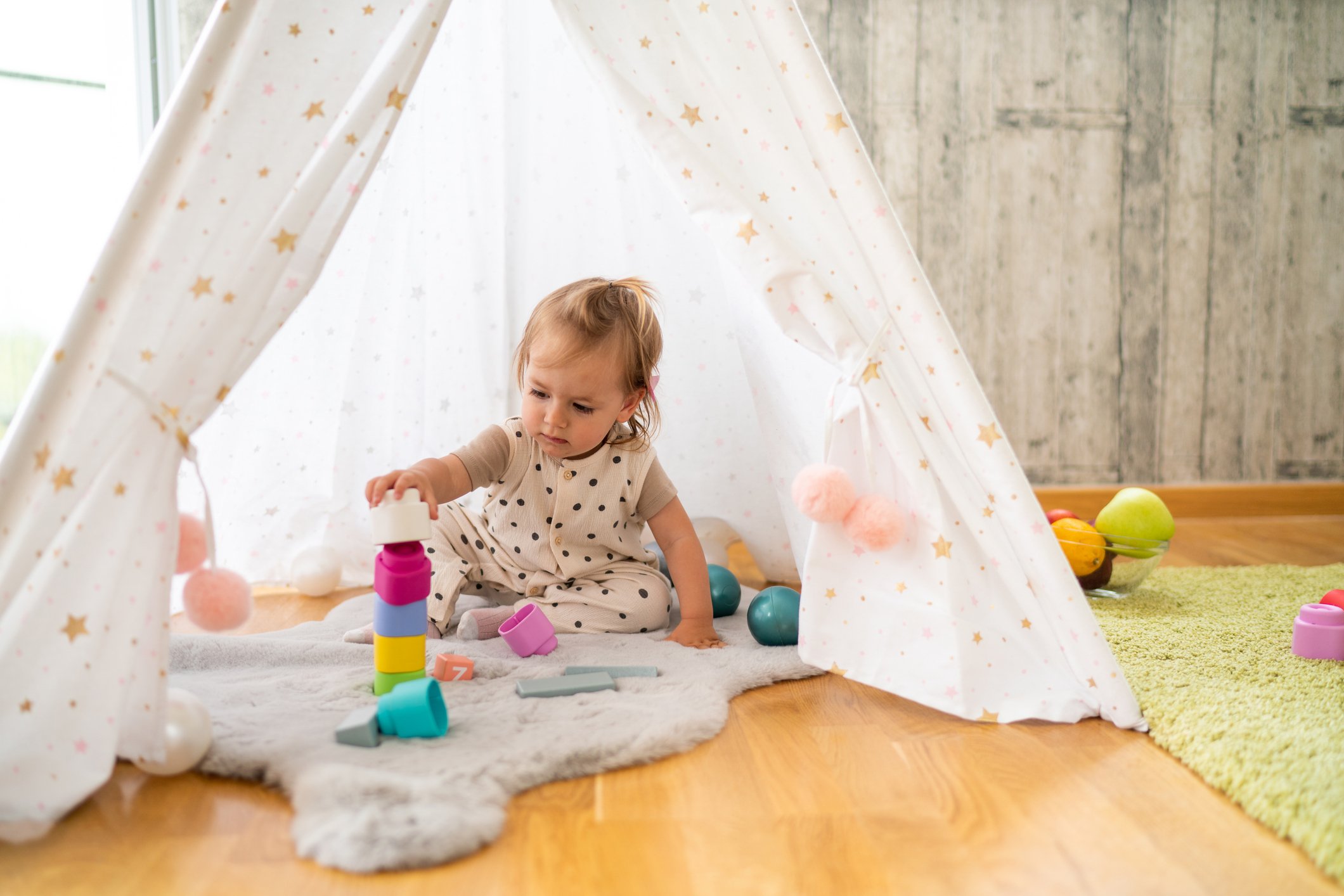 Cute baby girl playing in tent at home